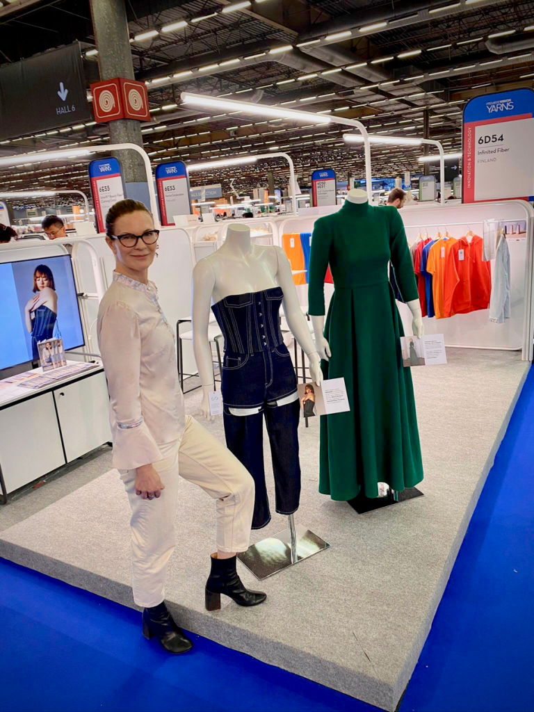 Woman standing beside two mannequins wearing clothes made from IFC fabric.